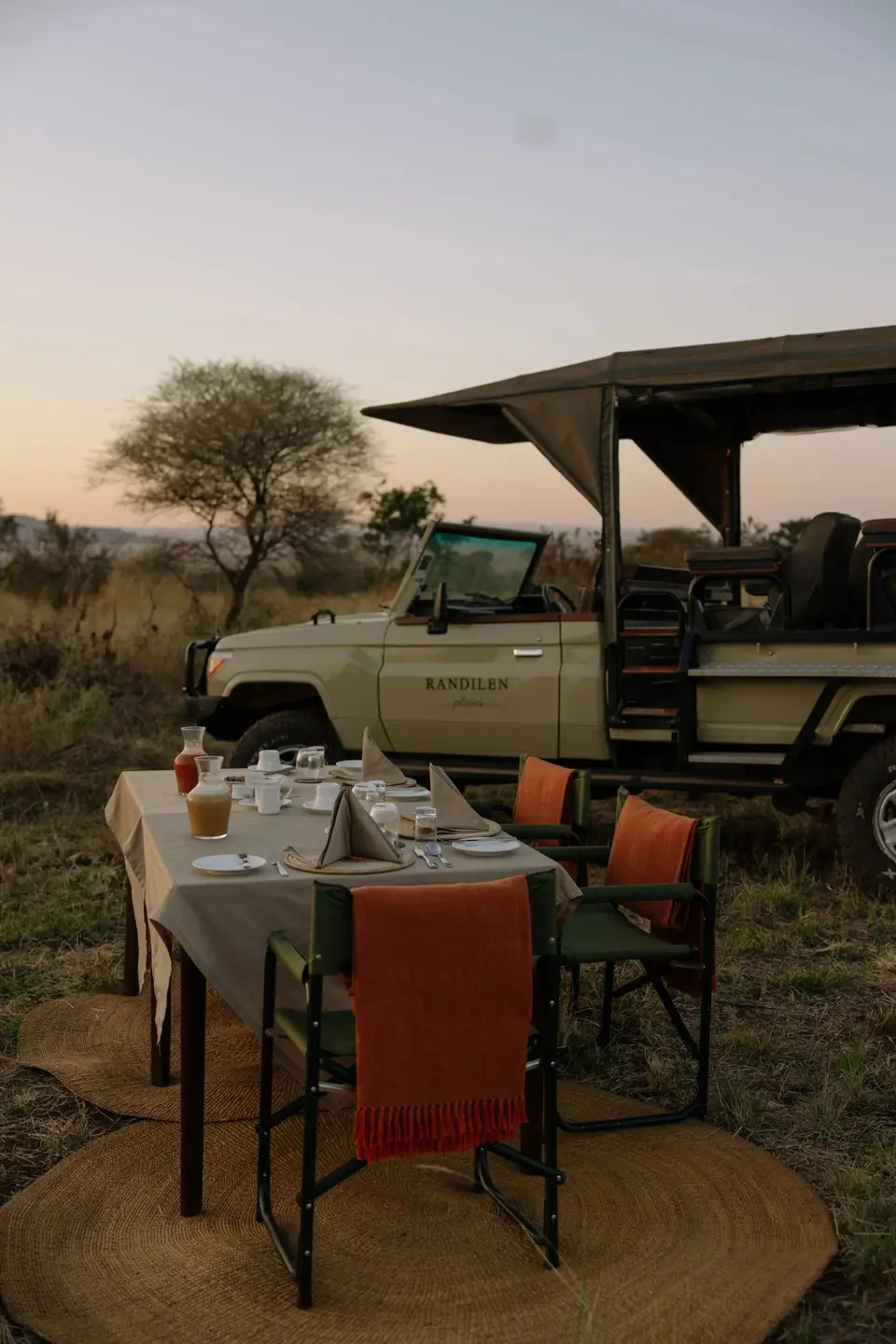 A table laid for breakfast in the bush beside a safari vehicle