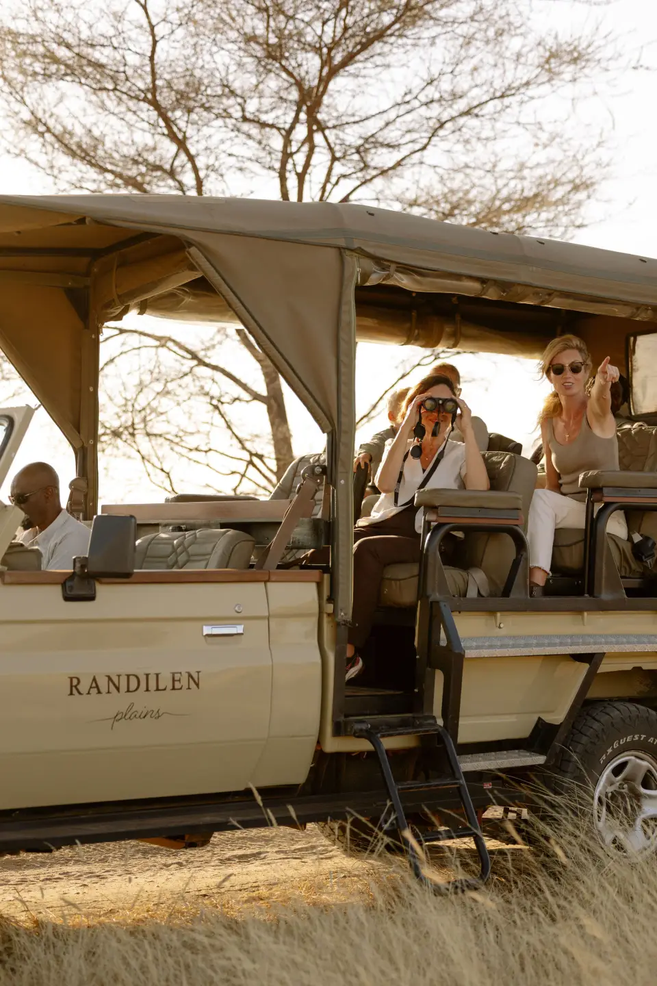 Two guests with binoculars and a camera in an open Randilen safari vehicle