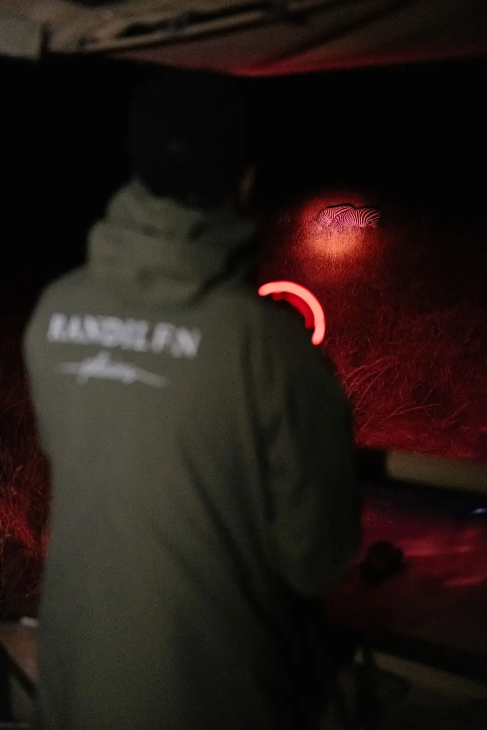 A guide in a Randilen jacket scans the dark with a red spotlight