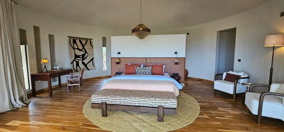 A banda bedroom with a king bed, woven rug and warm wooden floor
