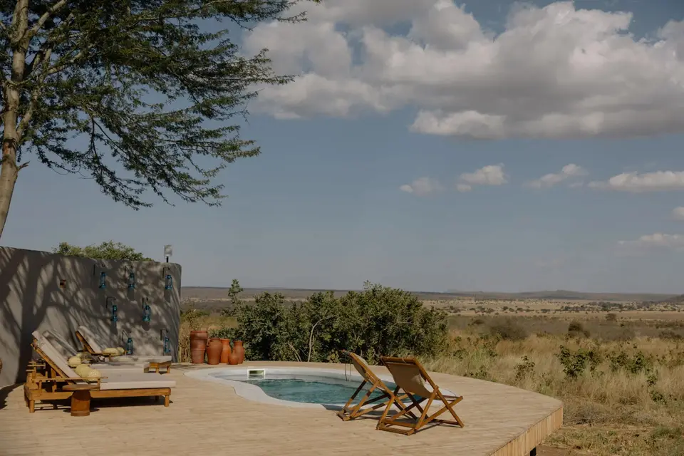 The lodge pool and loungers on a stone terrace under a wide sky