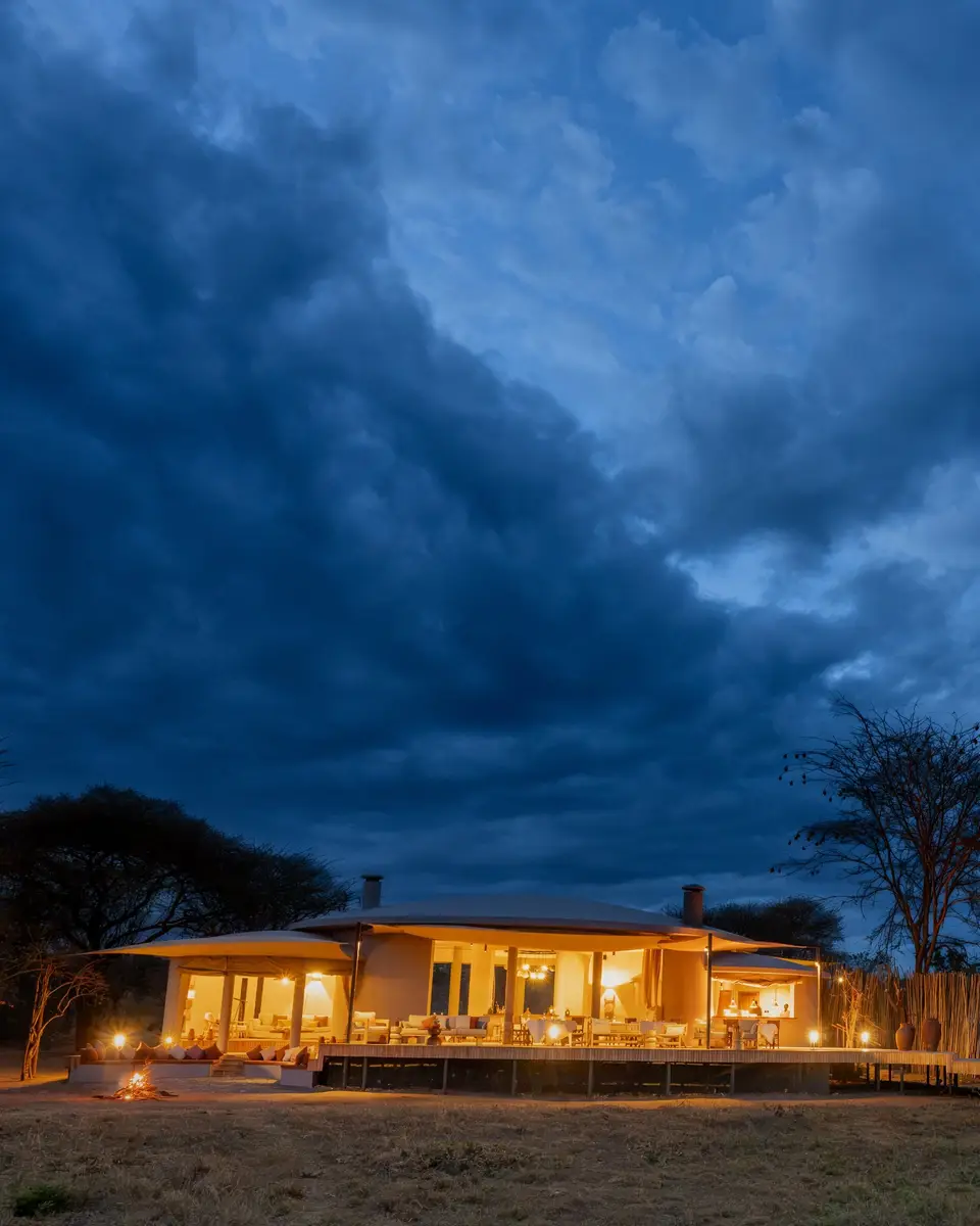 The main house at dusk, lamps lit between its columns